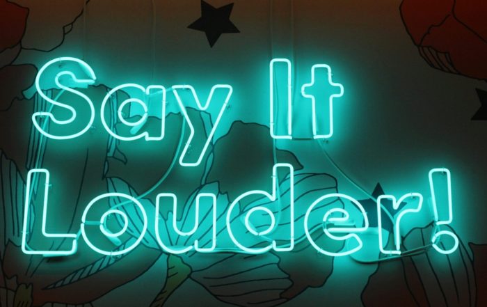 A blue neon sign reading Say It Louder, for “Learning to Say No: Our Boundaries and Self Care Workshop”