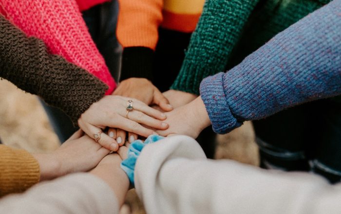 A group of women joining hands, for “Stand in Your Space: A Unique Group Coaching Journey for Women”